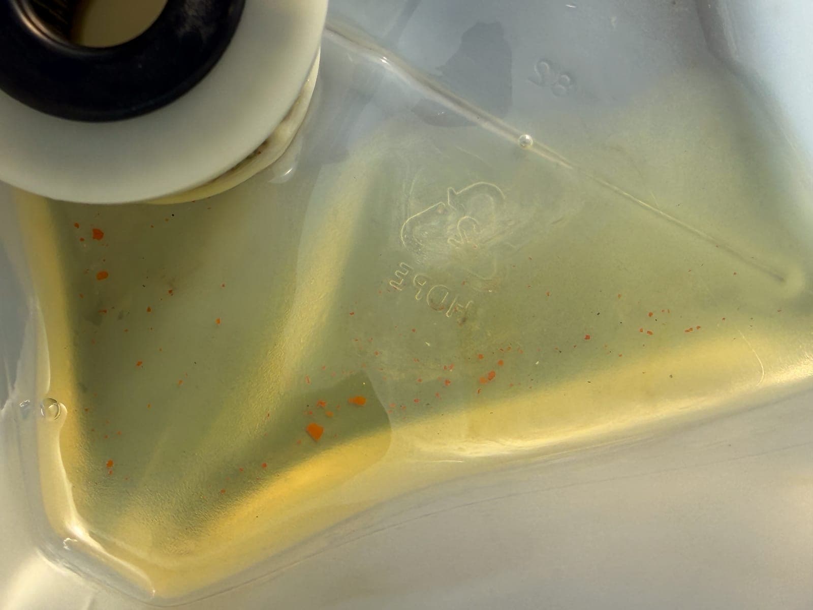 Used engine oil draining from an outboard at the 300-hour service interval, showing the metal-fleck and combustion debris that builds up between intervals